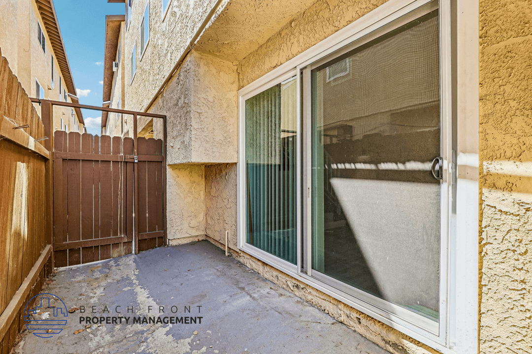 A balcony with a sliding door and a wooden fence.